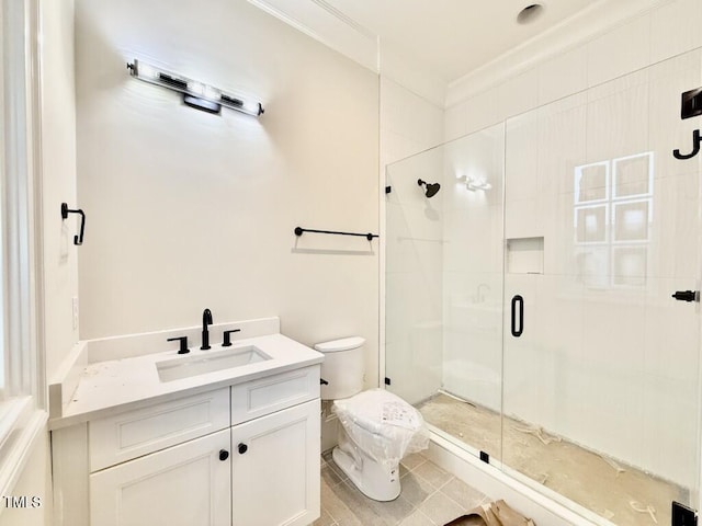 bathroom featuring a shower with shower door, vanity, toilet, crown molding, and tile patterned floors