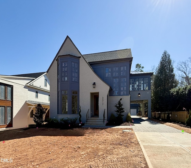 view of front of house featuring metal roof, a standing seam roof, driveway, and stucco siding