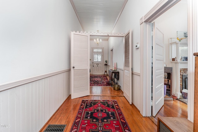 corridor featuring ornamental molding, a chandelier, and light wood-type flooring