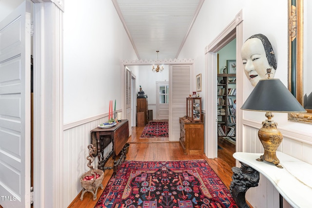 hallway with hardwood / wood-style flooring, ornamental molding, and a notable chandelier