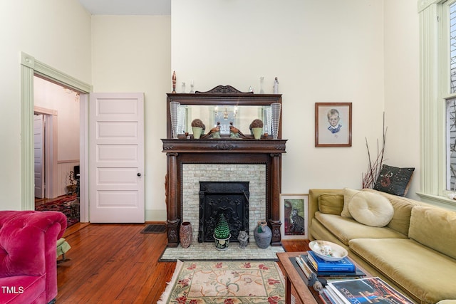 living room with a brick fireplace and dark hardwood / wood-style floors