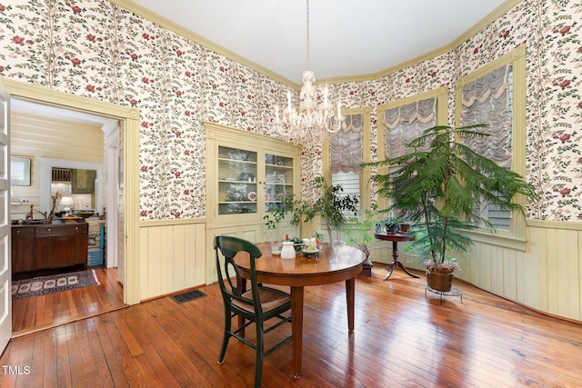 dining room featuring wood-type flooring, ornamental molding, and a chandelier