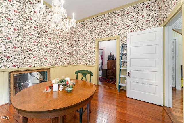 dining space with an inviting chandelier, wood-type flooring, and crown molding