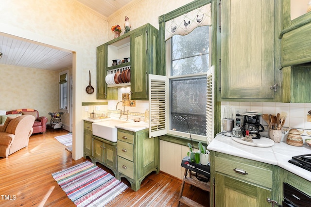 kitchen featuring sink, backsplash, light hardwood / wood-style floors, and green cabinets