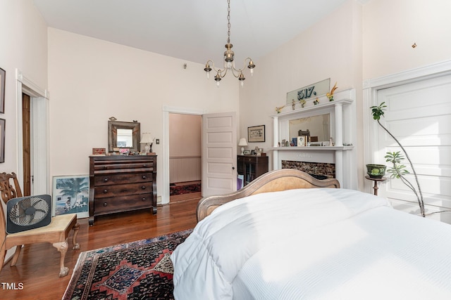 bedroom featuring a towering ceiling, dark hardwood / wood-style flooring, and a chandelier