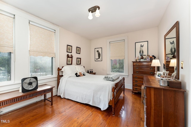 bedroom with multiple windows, hardwood / wood-style flooring, and a baseboard radiator