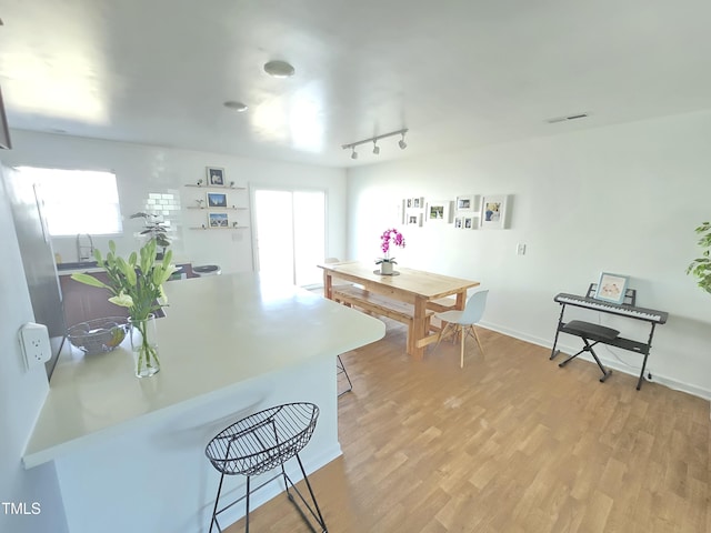 kitchen with rail lighting, light wood-type flooring, a breakfast bar area, and a healthy amount of sunlight