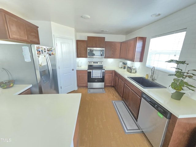 kitchen with appliances with stainless steel finishes, light hardwood / wood-style floors, and sink