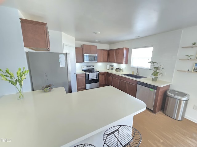 kitchen featuring light wood-type flooring, kitchen peninsula, sink, and stainless steel appliances