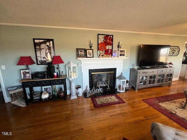 living room featuring a textured ceiling, crown molding, and hardwood / wood-style flooring