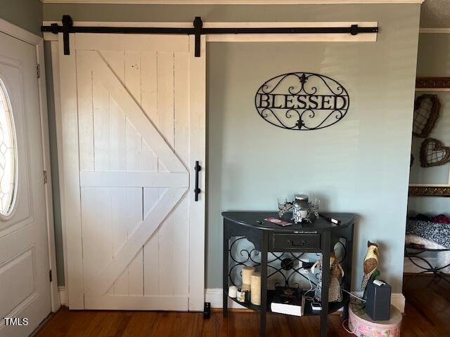 interior space with hardwood / wood-style floors, ornamental molding, and a barn door