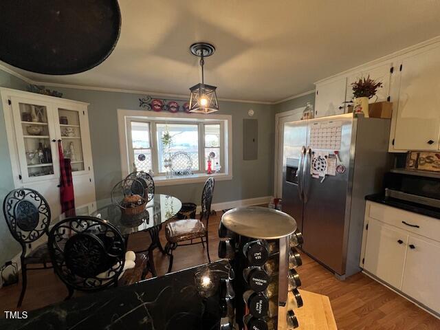 dining room with light hardwood / wood-style floors, electric panel, and ornamental molding