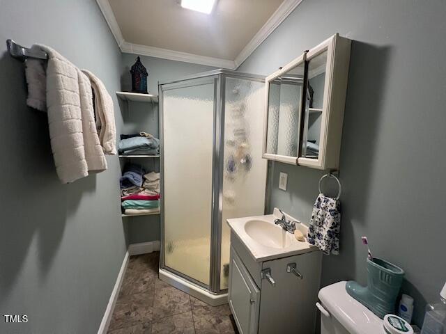 bathroom featuring a shower with door, toilet, vanity, and crown molding