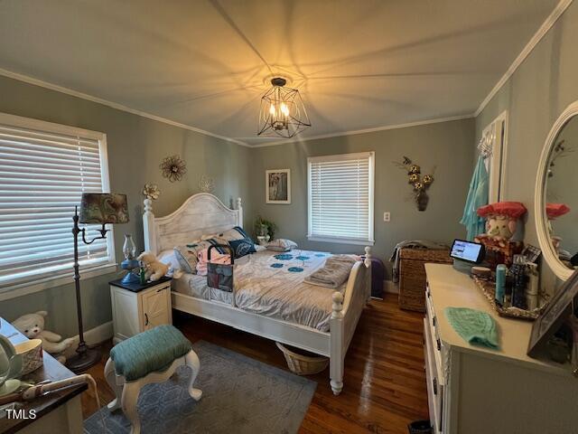 bedroom featuring dark hardwood / wood-style flooring, crown molding, and a notable chandelier