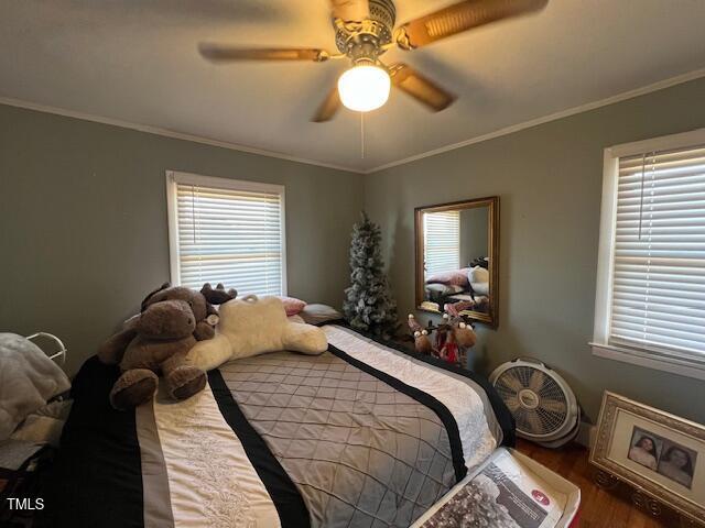 bedroom with ceiling fan, wood-type flooring, and ornamental molding