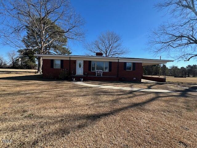 ranch-style house featuring a front lawn and a carport