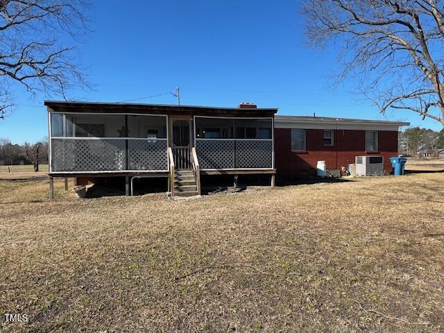 back of property with a lawn and a sunroom