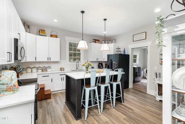 kitchen with a center island, decorative backsplash, sink, hanging light fixtures, and white cabinets