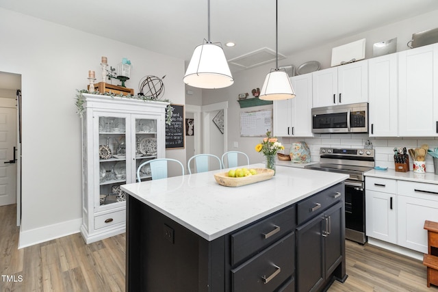 kitchen with white cabinetry, stainless steel appliances, tasteful backsplash, a kitchen island, and pendant lighting