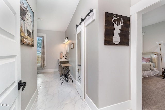 hallway featuring light carpet and a barn door