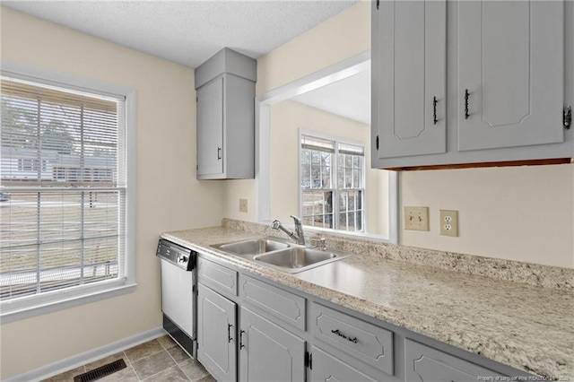 kitchen with sink, gray cabinetry, dishwashing machine, and a textured ceiling