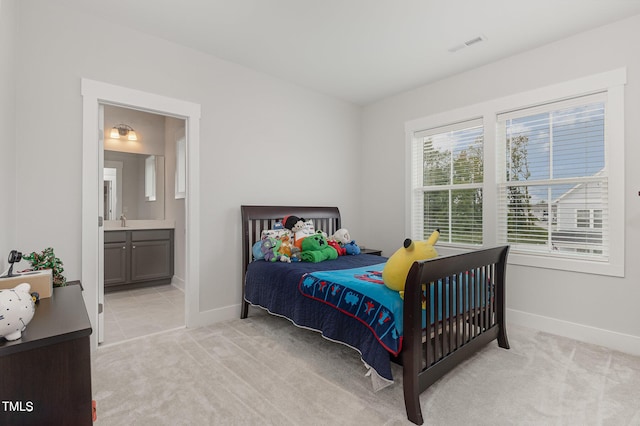 carpeted bedroom featuring ensuite bathroom and sink