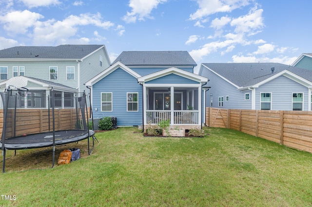 back of house featuring a sunroom, a yard, and a trampoline