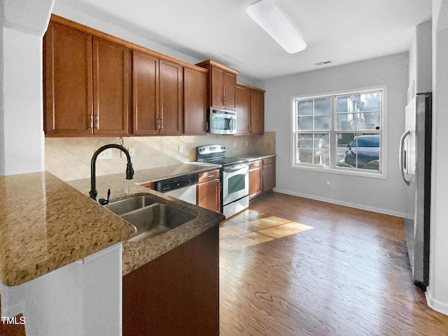 kitchen featuring sink, backsplash, kitchen peninsula, and appliances with stainless steel finishes