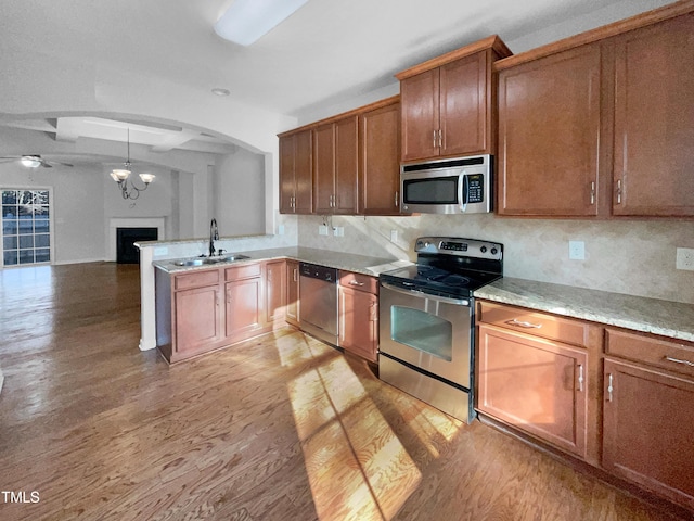 kitchen with sink, light wood-type flooring, appliances with stainless steel finishes, and decorative backsplash