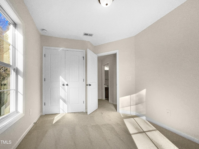 unfurnished bedroom featuring light colored carpet and a closet