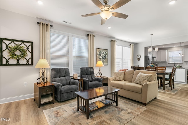 living room with light hardwood / wood-style flooring and ceiling fan