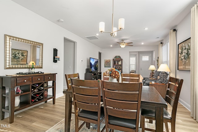 dining room with ceiling fan with notable chandelier and light hardwood / wood-style floors