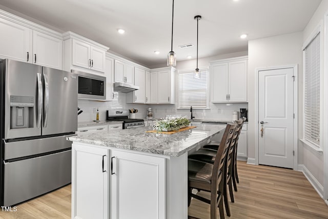 kitchen featuring white cabinetry, hanging light fixtures, stainless steel appliances, and a center island