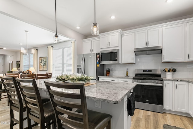 kitchen featuring white cabinetry, stainless steel appliances, a breakfast bar, and hanging light fixtures