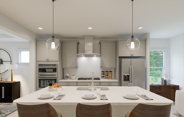 kitchen featuring appliances with stainless steel finishes, wall chimney exhaust hood, hanging light fixtures, and gray cabinets