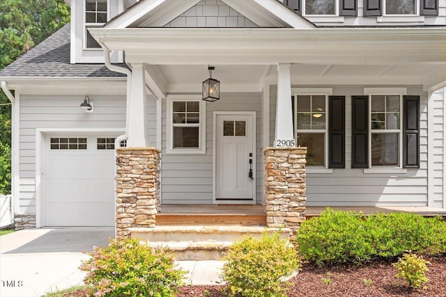 2905 Cammie St, Durham, NC 27705 - property entrance with covered porch, a shingled roof, concrete driveway, an attached garage, and stone siding