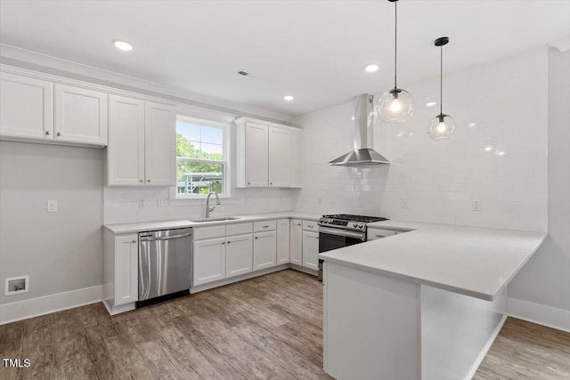 2905 Cammie St, Durham, NC 27705 - kitchen featuring appliances with stainless steel finishes, wall chimney range hood, a peninsula, light wood-style floors, and white cabinetry