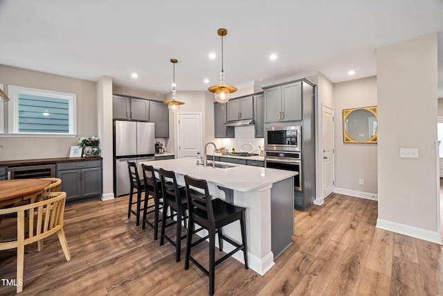 kitchen featuring hardwood / wood-style flooring, pendant lighting, appliances with stainless steel finishes, and gray cabinetry