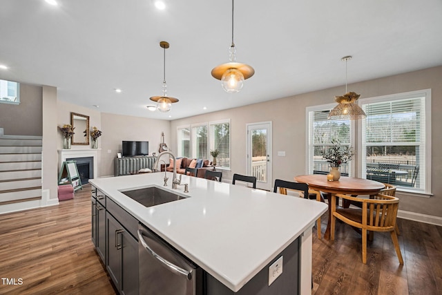 kitchen featuring sink, a center island with sink, stainless steel dishwasher, and decorative light fixtures