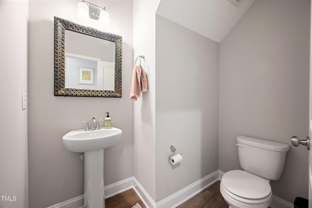 bathroom featuring sink, hardwood / wood-style floors, toilet, and vaulted ceiling