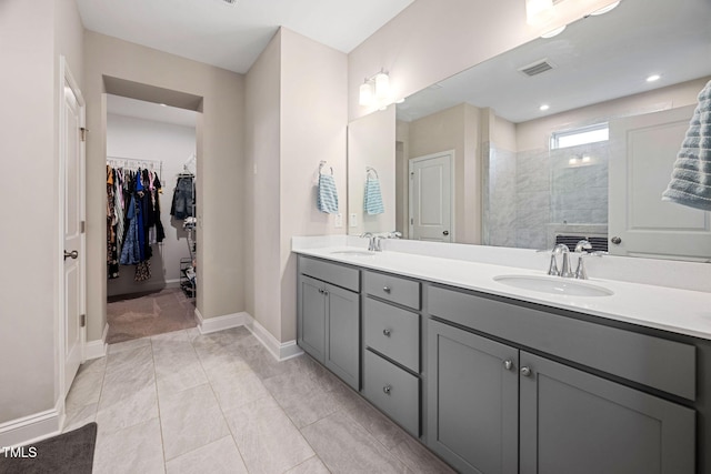 bathroom with tile patterned floors, vanity, and a tile shower