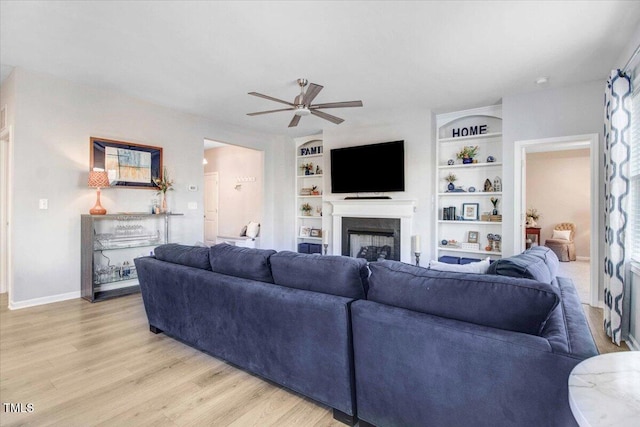 living room with ceiling fan, built in features, and light hardwood / wood-style flooring