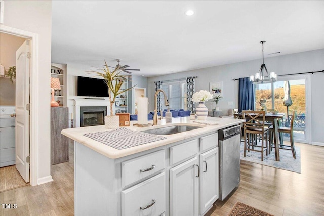 kitchen with white cabinetry, light hardwood / wood-style floors, an island with sink, stainless steel dishwasher, and sink