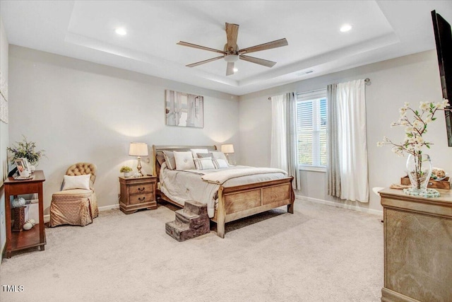 bedroom with ceiling fan, a tray ceiling, and light carpet