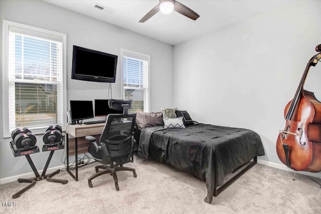 bedroom featuring ceiling fan, light colored carpet, and multiple windows