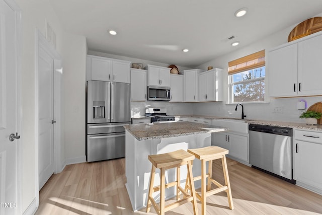 kitchen featuring stainless steel appliances, a center island, a breakfast bar area, and white cabinets