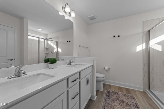 bathroom featuring vanity, toilet, hardwood / wood-style floors, and a shower with shower door