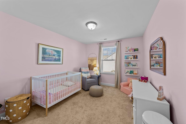 carpeted bedroom featuring a nursery area