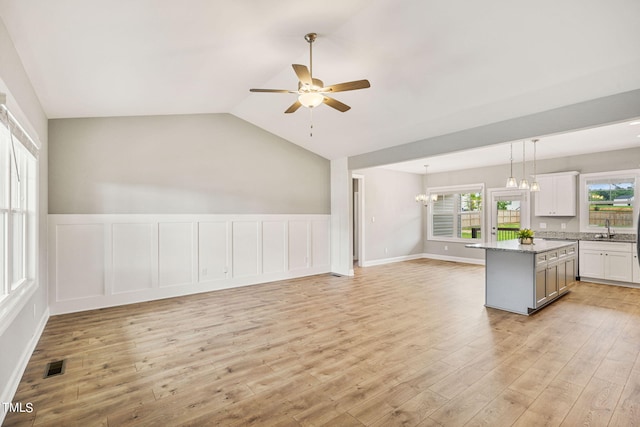 kitchen with hanging light fixtures, white cabinets, a center island, light hardwood / wood-style floors, and lofted ceiling