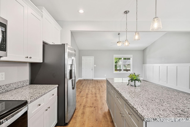 kitchen featuring white cabinetry, light wood-type flooring, decorative light fixtures, a kitchen island, and light stone counters